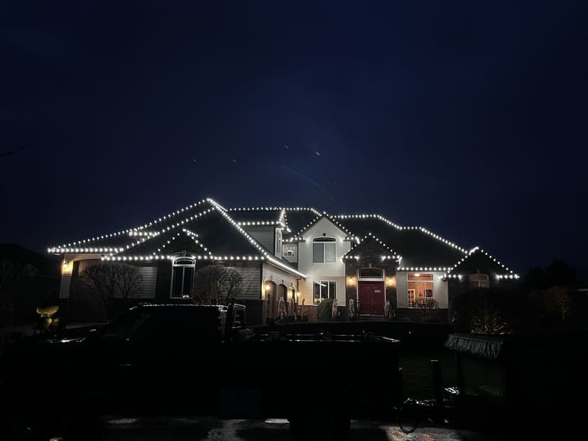 House beautifully decorated with white string lights for nighttime ambiance.